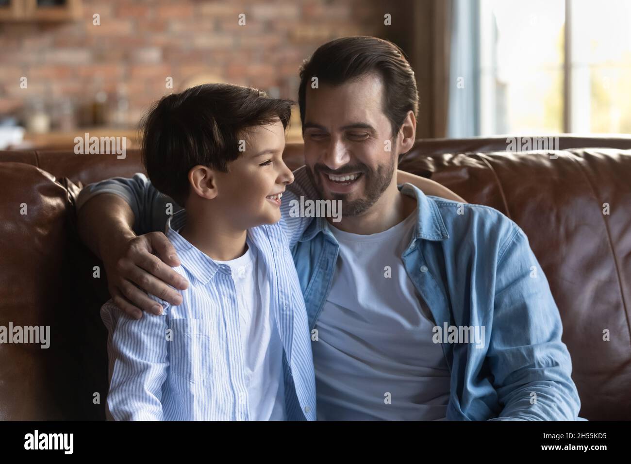 Buon padre giovane abbraccia il figlio piccolo godere di conversazione con il bambino Foto Stock
