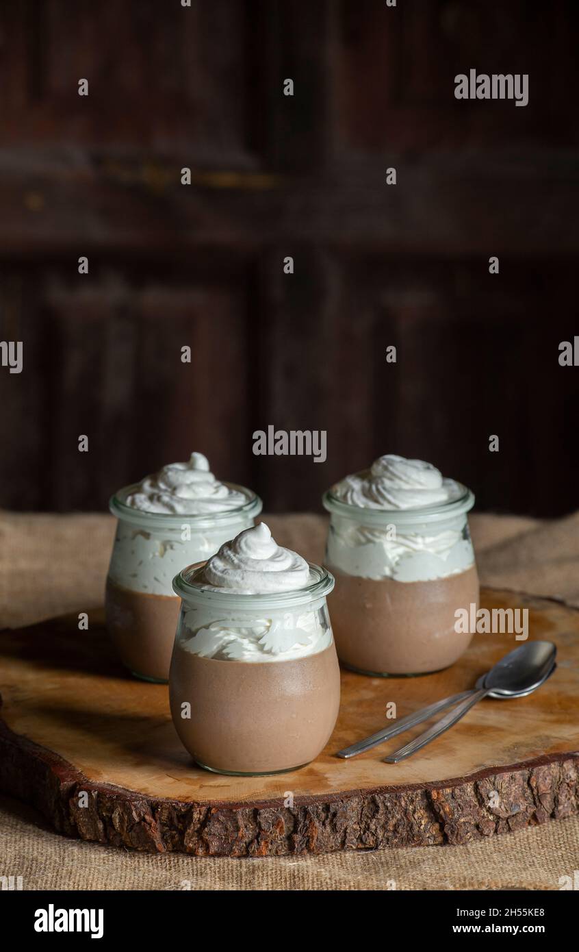 Mousse al cioccolato, tre contenitori di vetro con questo delizioso dessert, tavolo e sfondo in legno d'epoca, spazio per copie. Foto Stock
