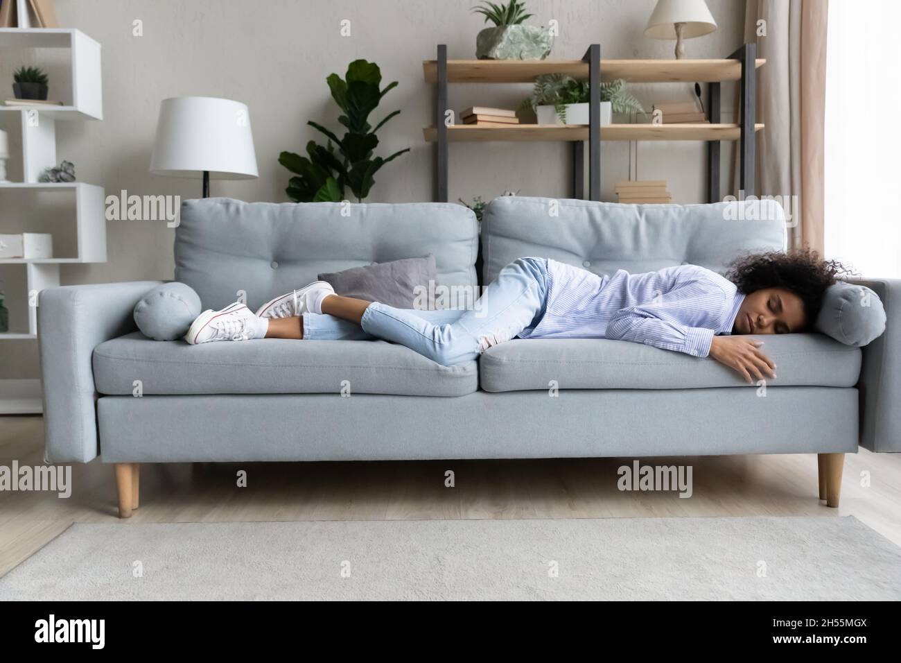 Donna afro-americana a tutta lunghezza che dorme su un comodo divano Foto Stock