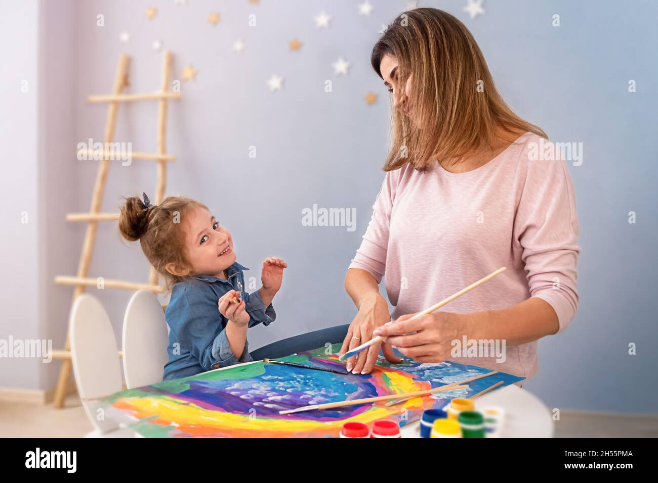 Una donna e una ragazza dipingono un arcobaleno sulla carta. Lezioni di pittura a Cholet. Spazio di copia per il progetto. Foto Stock