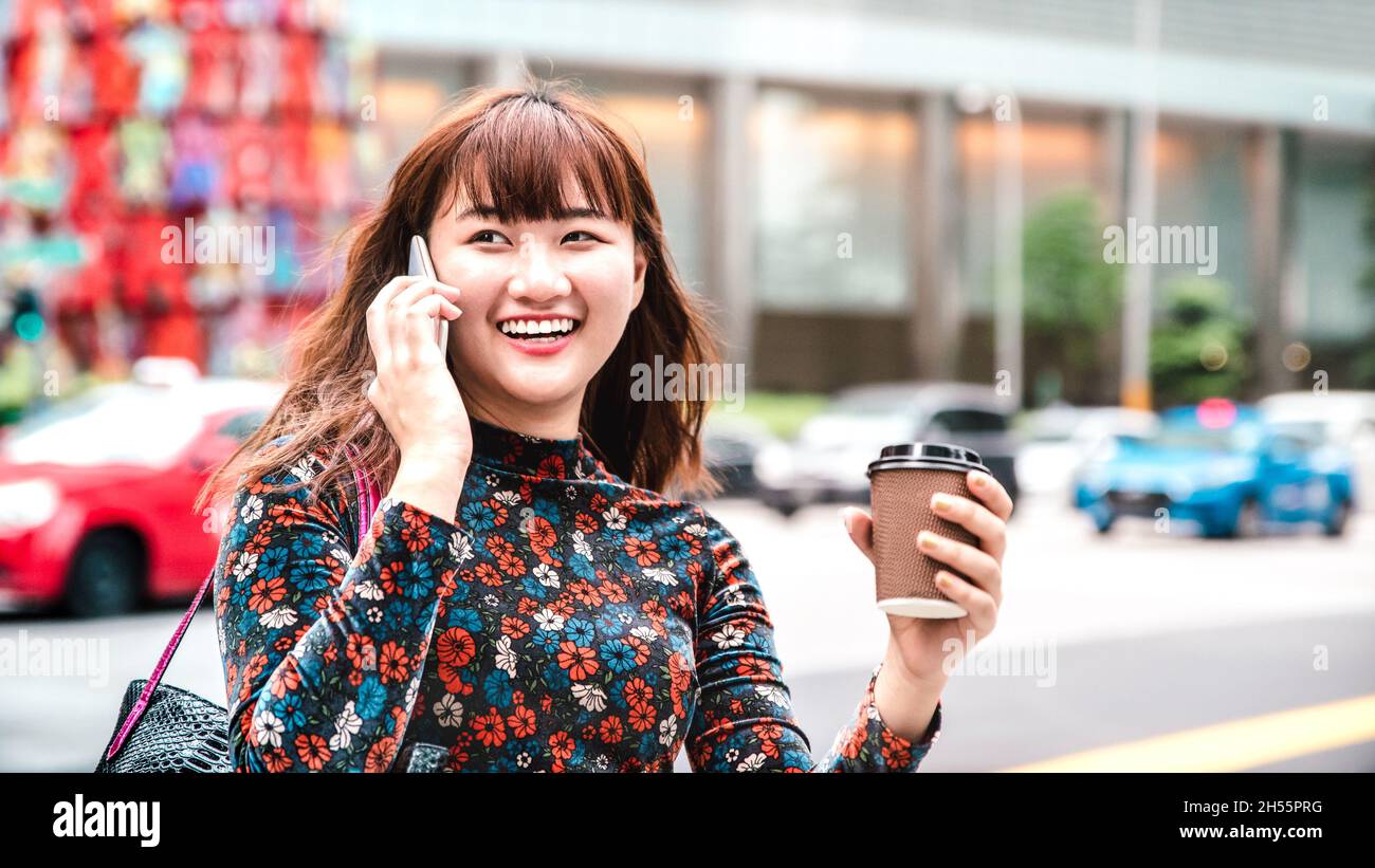 Giovane donna asiatica che usa lo smart phone mobile a Singapore City Streets - tecnologia stile di vita concetto con ragazza felice che ha divertente chiamata in città Foto Stock