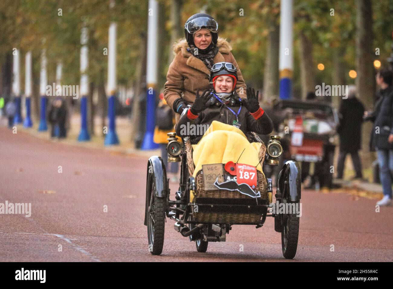 Westminster, Londra, Regno Unito. 7 novembre 2021. I passeggeri di un Phoenix Tricar del 1904 con sedile passeggero con paniere in vimini nella parte anteriore sono chiaramente godendo il loro viaggio. Le auto veterane sul Mall, che conducono lontano da Buckingham Palace. Quest'anno si celebra il 125° anniversario della storica London to Brighton Veteran Car Run. Per segnare l’occasione, più di 320 pionieristiche “carrozze senza cavalli” dall’alba dell’automobilismo Hyde Park a Londra all’alba e faranno lo stesso viaggio a Brighton sulla costa del Sussex. Credit: Imagplotter/Alamy Live News Foto Stock