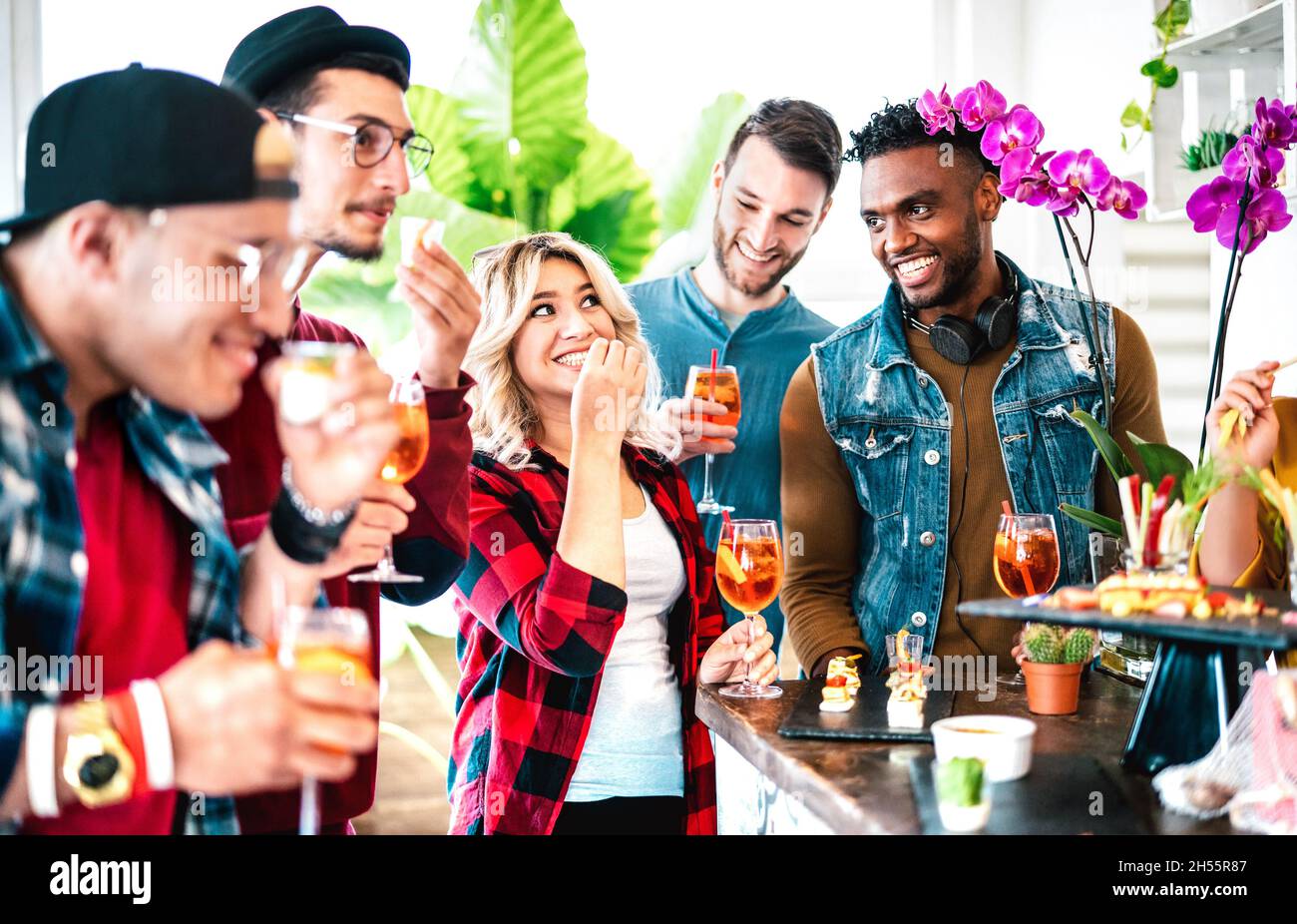 Gruppo di amici multiculturali che si divertono prima di cena con aperitivo a buffet che beve cocktail e mangiare spuntini - People stile di vita concetto Foto Stock