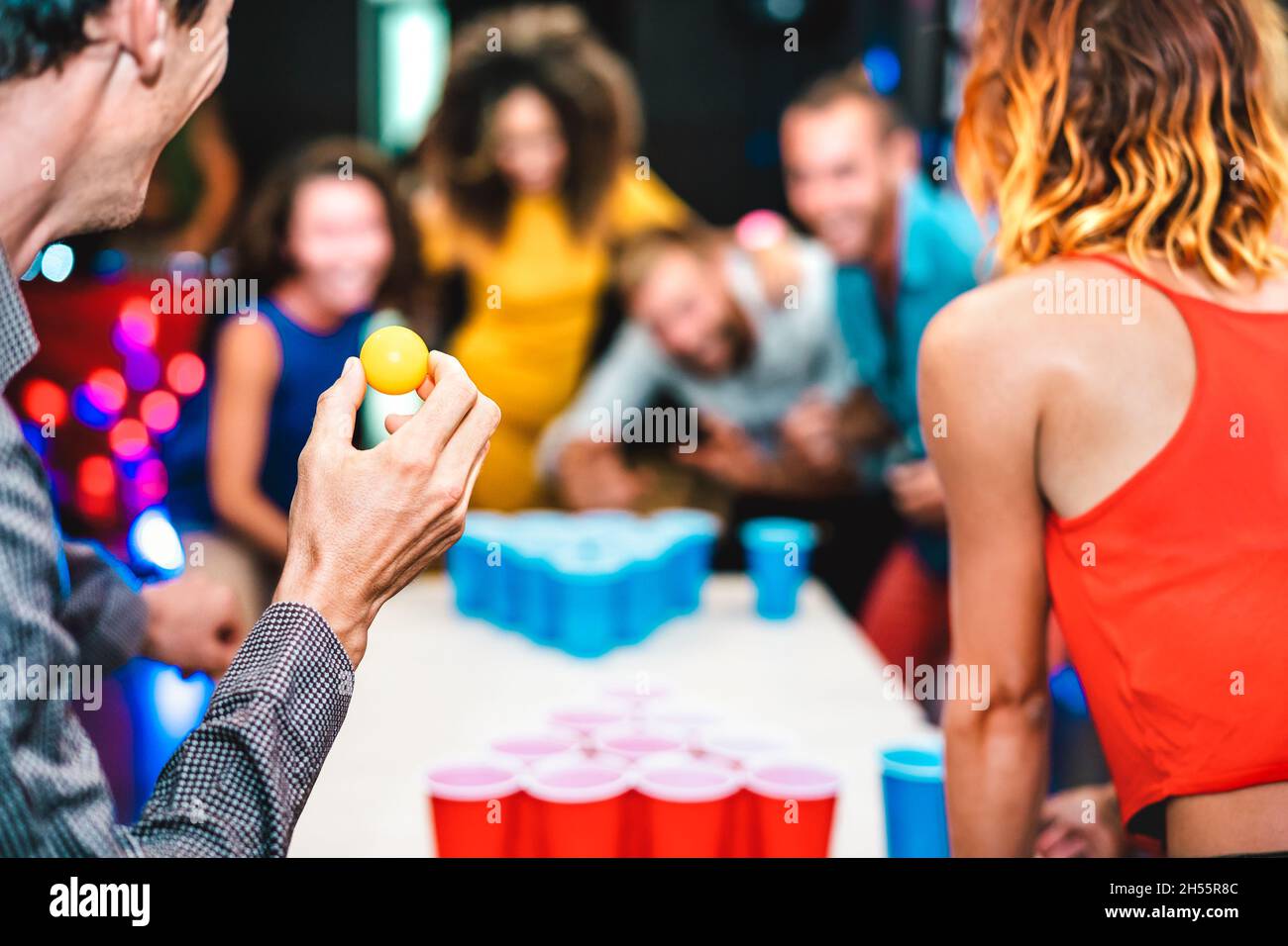 Sfondo sfocato di giovani amici giocando birra pong a ostello della gioventù - concetto di viaggio tempo libero con backpackers che hanno divertimento genuino in pensione Foto Stock