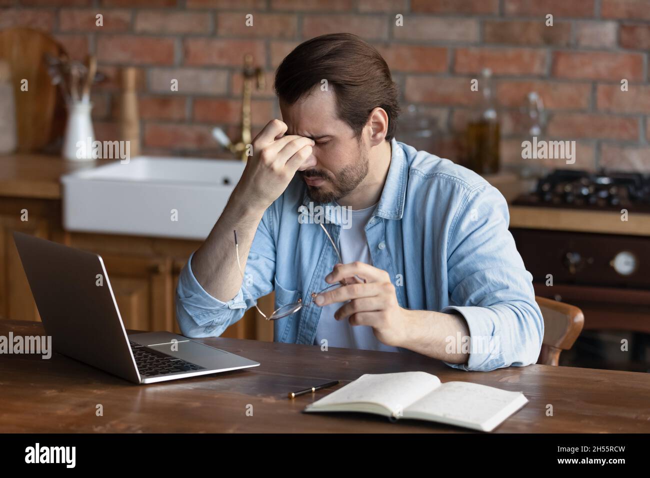 Il freelance maschile ha superato il lavoro del laptop Feel Bad togliere gli occhiali Foto Stock