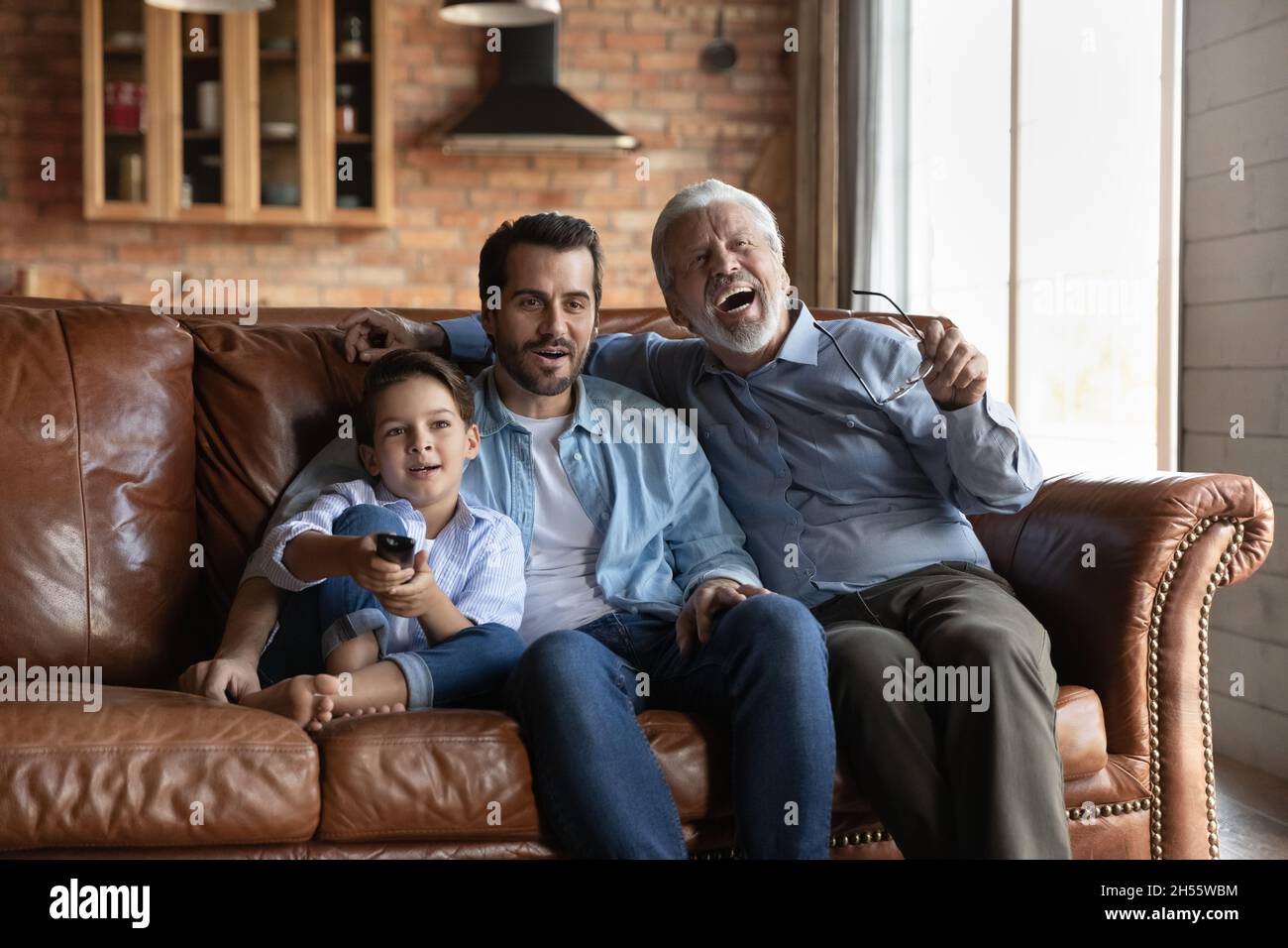 Tre membri maschi della famiglia multi generazionale che guardano la tv insieme Foto Stock