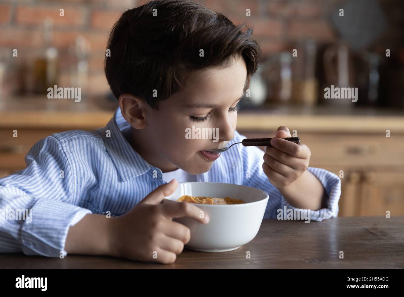 Ragazzo preda affamato che ha buon appetito mangiando cereali con latte Foto Stock