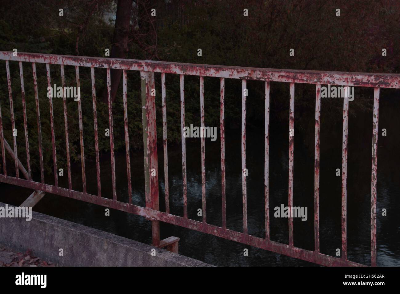 vecchio e arrugginito ponte che scorre sul fiume tranquillo in serata buia Foto Stock