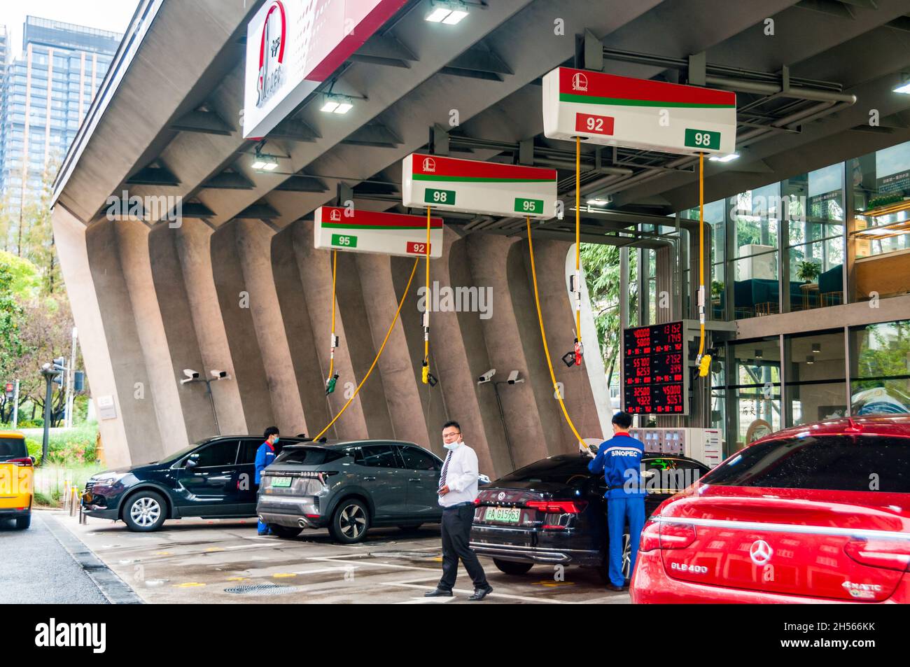 Auto, principalmente ibridi plug-in placcati in verde, che si riempiono presso una stazione di servizio Sinopec nel centro di Shanghai, in Cina. Foto Stock