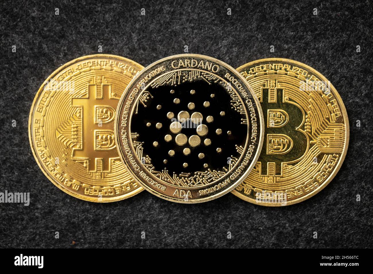 Moneta di Cardano Ada che si adagia sopra due bitcoin. Foto Stock