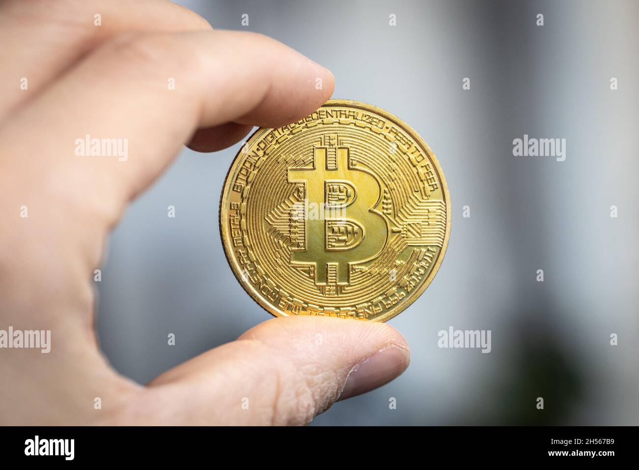Moneta di criptovaluta Bitcoin tenuta tra due dita Foto Stock