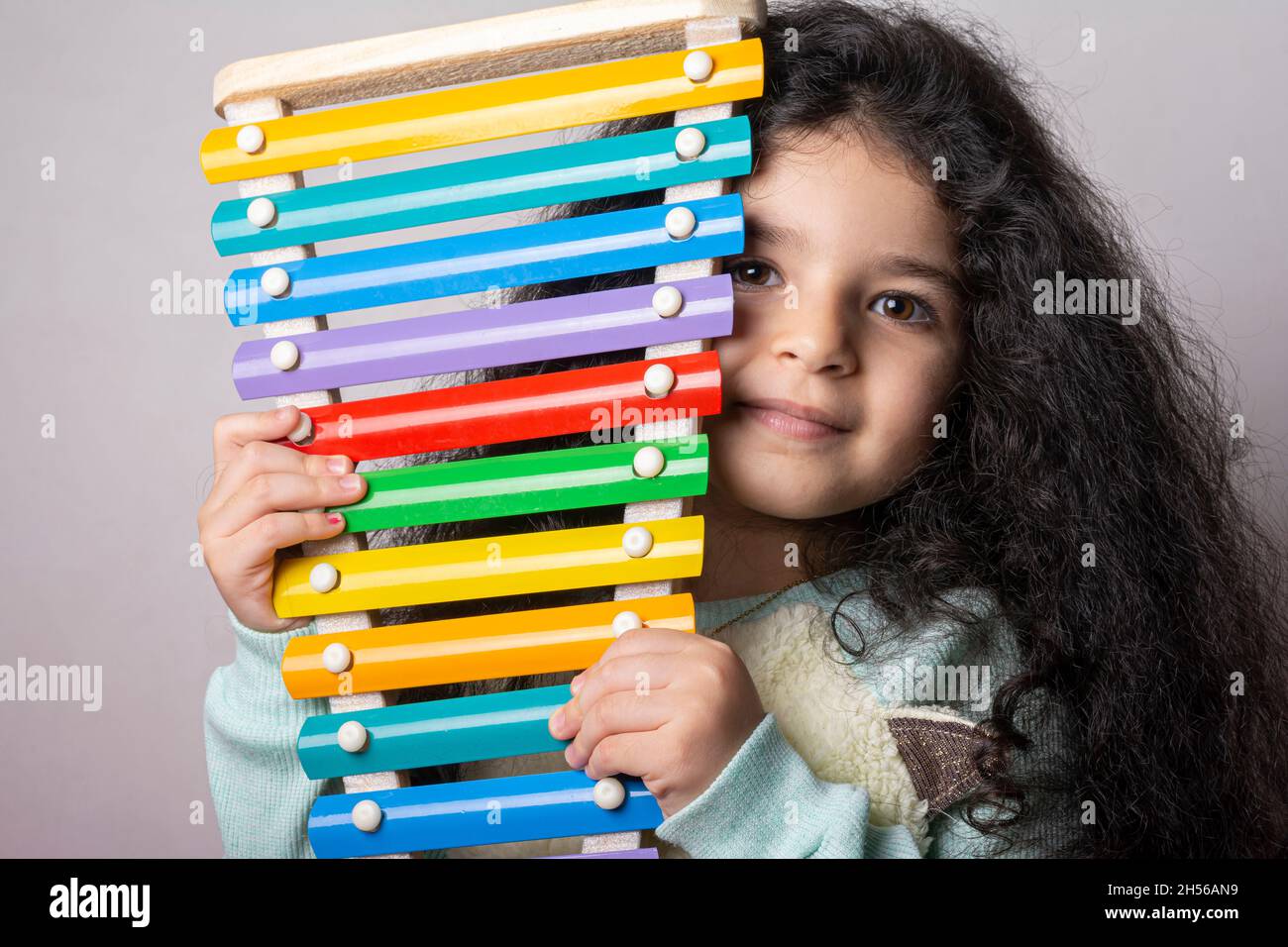 Ritratto di bambina con xylophone in mano guardando in macchina fotografica con espressione, ricordi d'infanzia Foto Stock