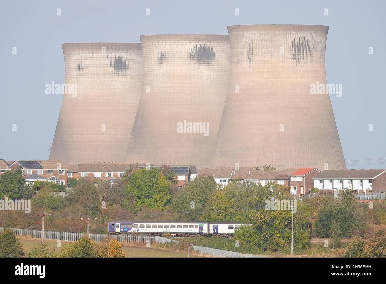 Un treno Northern Rail passa di fronte a Wentcliffe Estate e le 3 torri di raffreddamento rimanenti della Centrale di Ferrybridge in programma per la demolizione Foto Stock