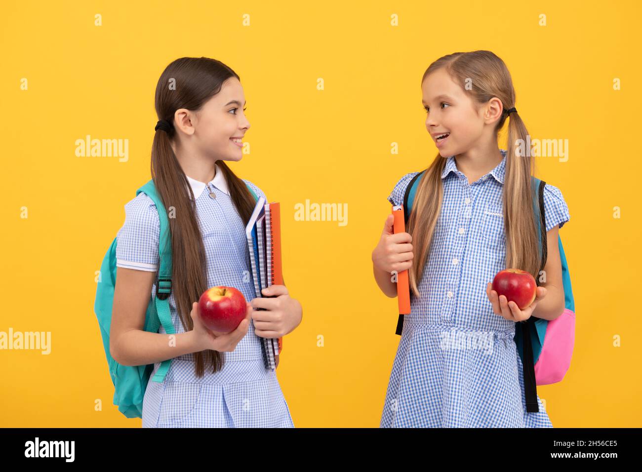 I bambini felici amici di nuovo a scuola tenendo libri e mele per una dieta sana, dieta Foto Stock