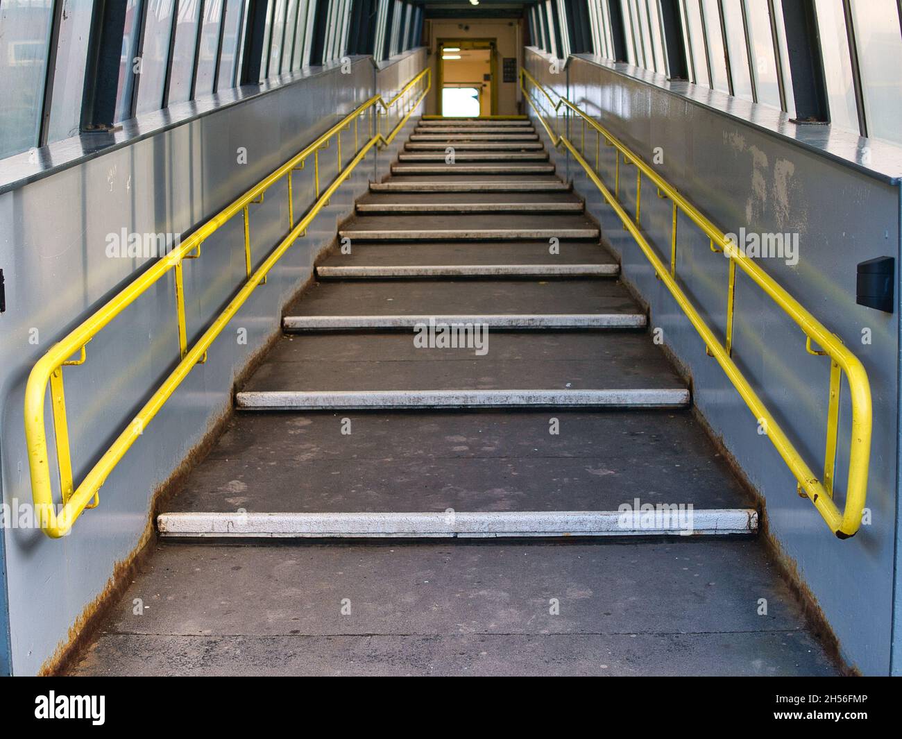 Una rampa a gradini con corrimano gialli consente di accedere a una piattaforma della stazione su una rete ferroviaria regionale. Foto Stock