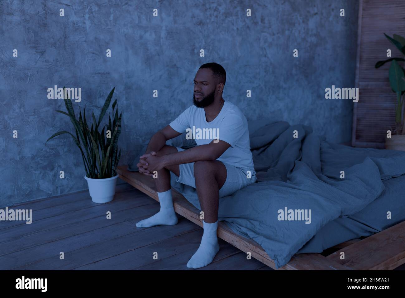 Uomo nero seduto a letto e pensando Foto Stock