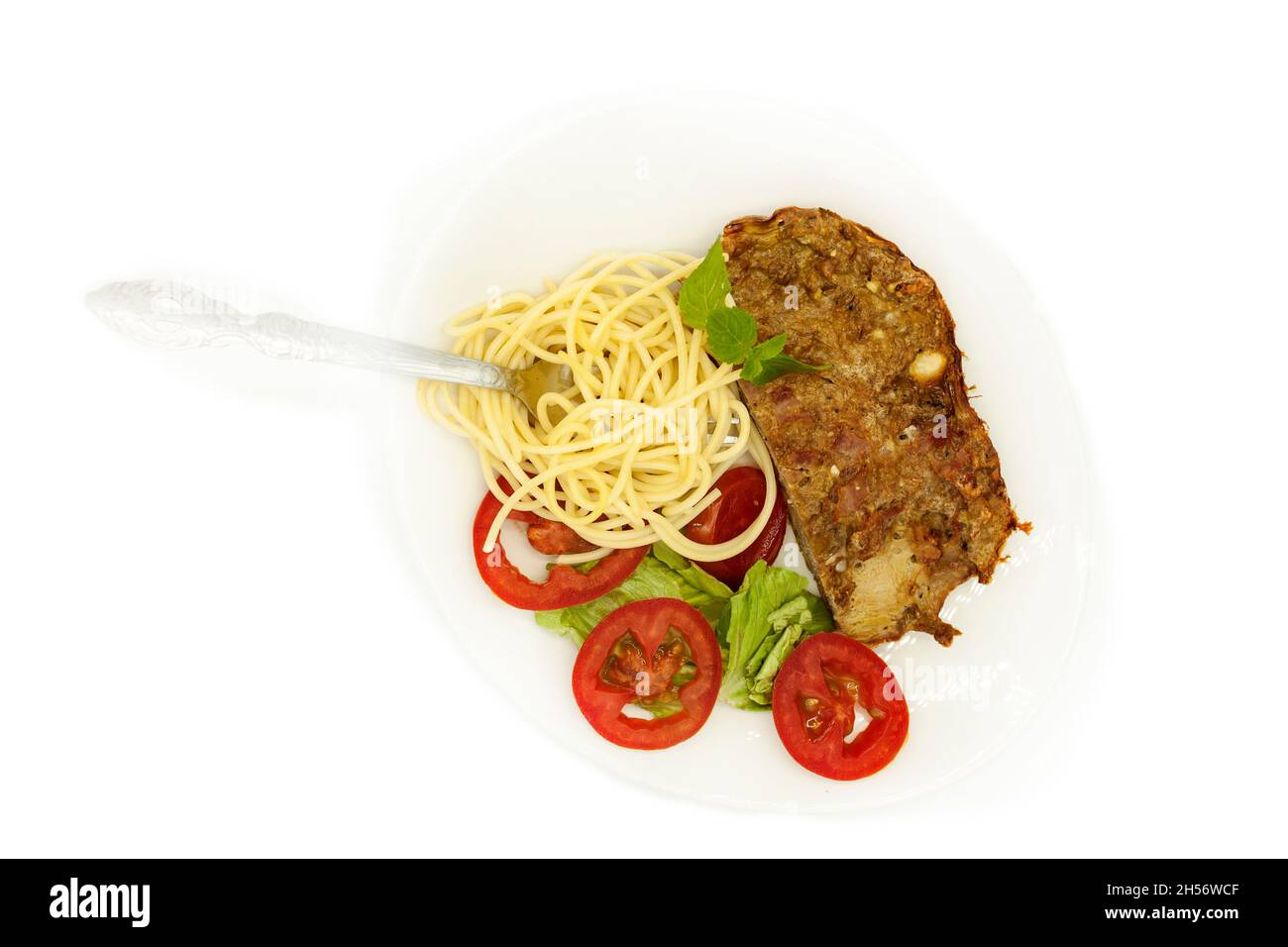 cena a base di carne di manzo piccante con fette salate servita con spaghetti e insalata di lattuga con pomodoro Foto Stock