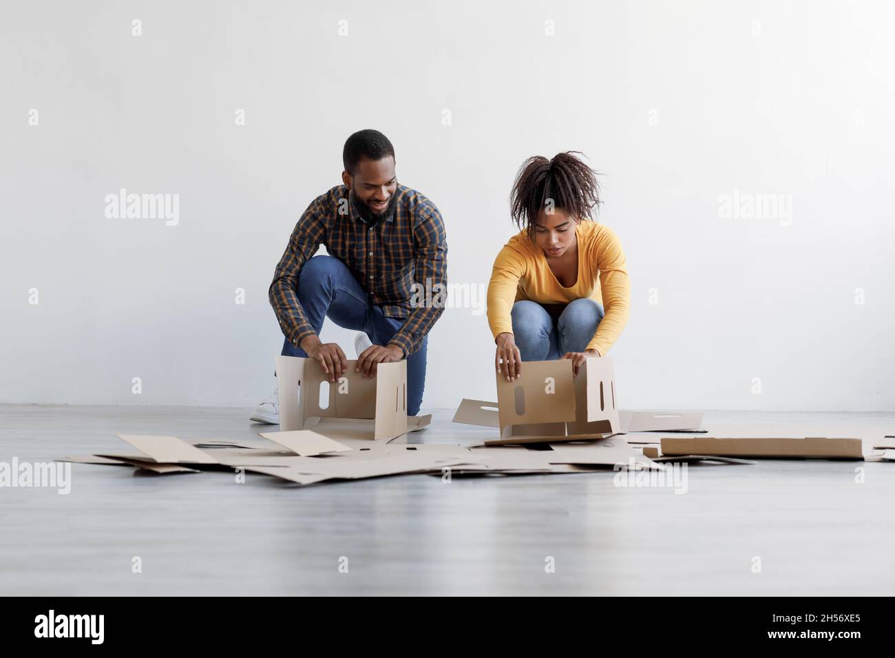 I giovani neri della famiglia impilano le scatole di cartone e si preparano a muoversi verso la nuova sede. Ristrutturazione, riposizionamento e acquisto di nuova casa Foto Stock