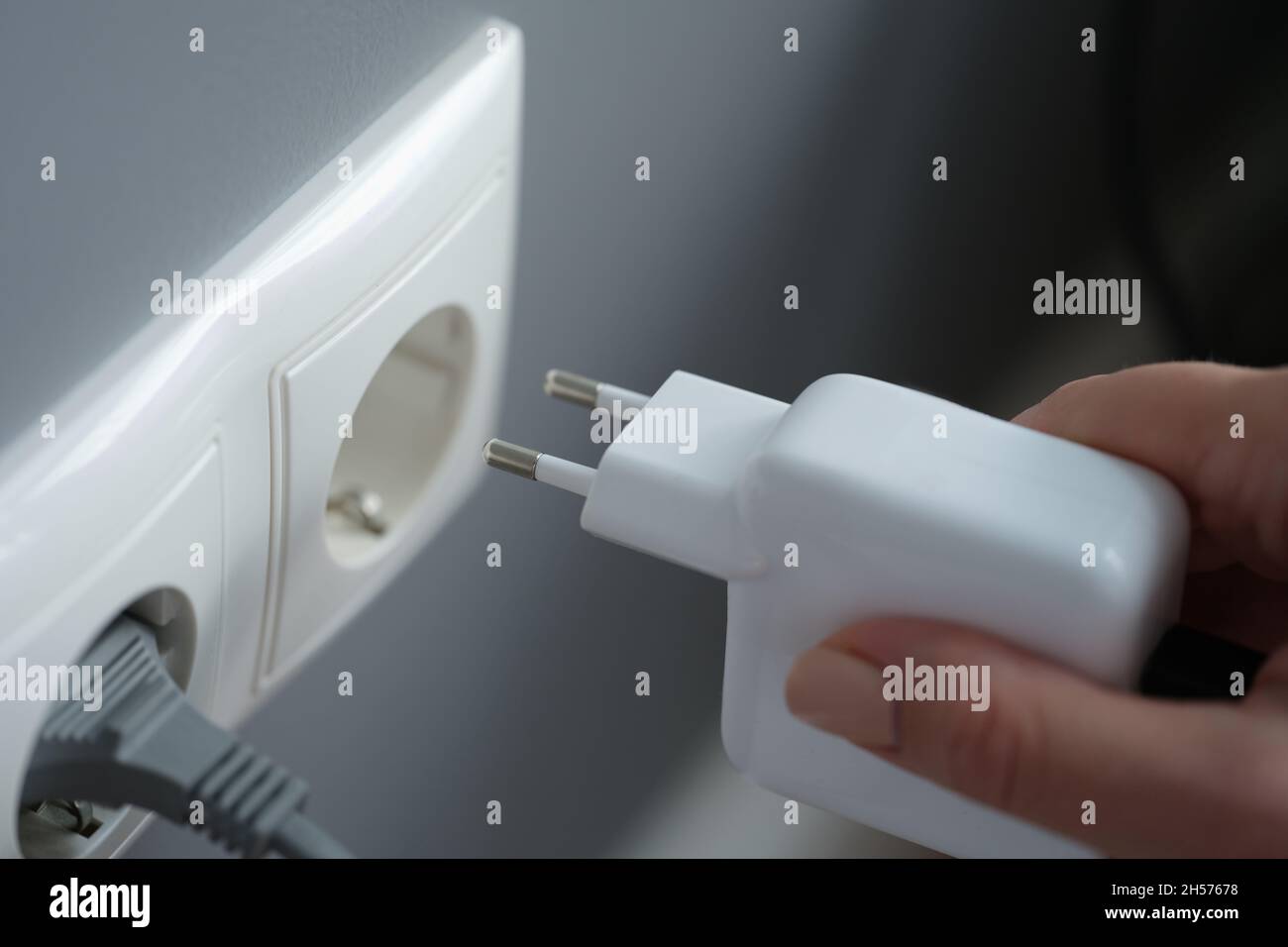 Collegare il caricabatterie a una presa a muro, in primo piano Foto Stock