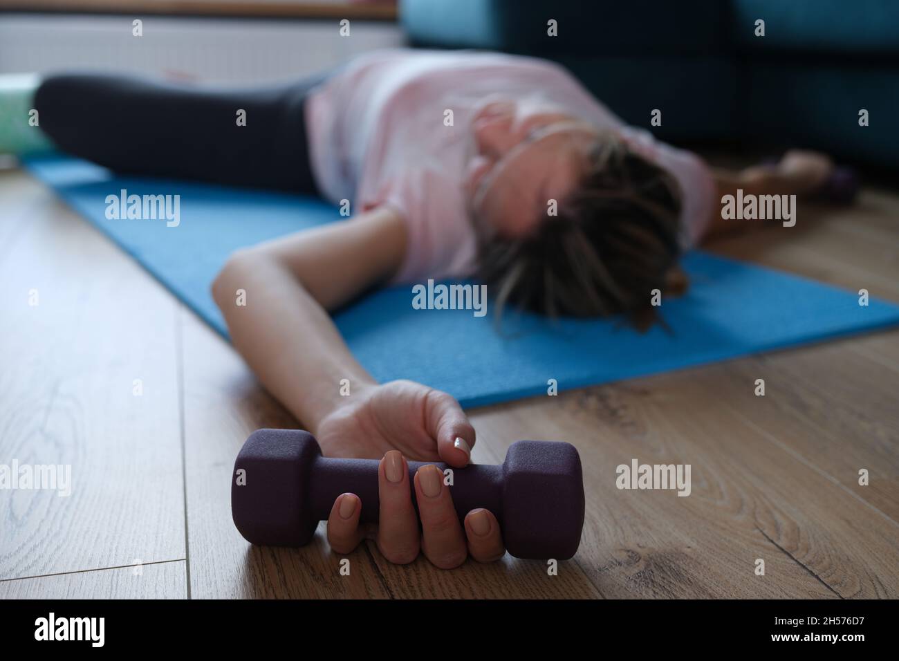 Una donna si trova su un tappeto con manubri in mano Foto Stock
