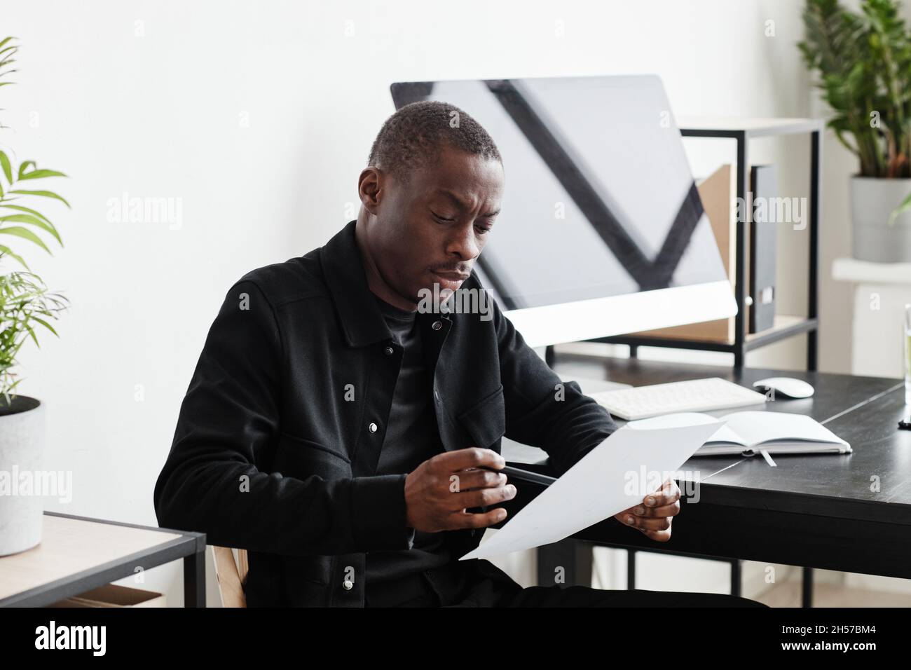 Ritratto minimo di un uomo d'affari nero di successo che guarda la fotocamera mentre lavora alla scrivania in ufficio, spazio copia Foto Stock