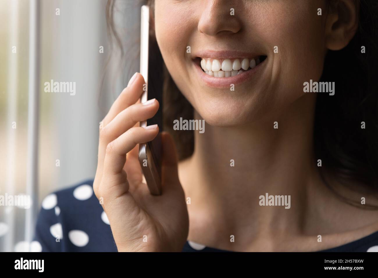 Primo piano di sorridente giovane signora che ha una bella conversazione telefonica Foto Stock