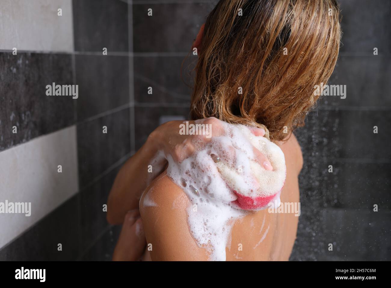 Donna in doccia con una spugna saponata lava il suo corpo Foto stock - Alamy