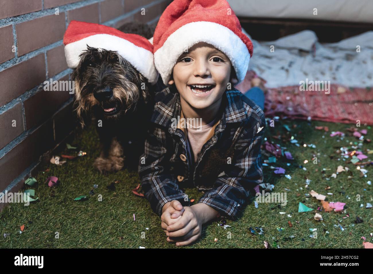 Bambino felice festeggia la festa di Natale con il cane da compagnia - Focus sul volto del ragazzo Foto Stock
