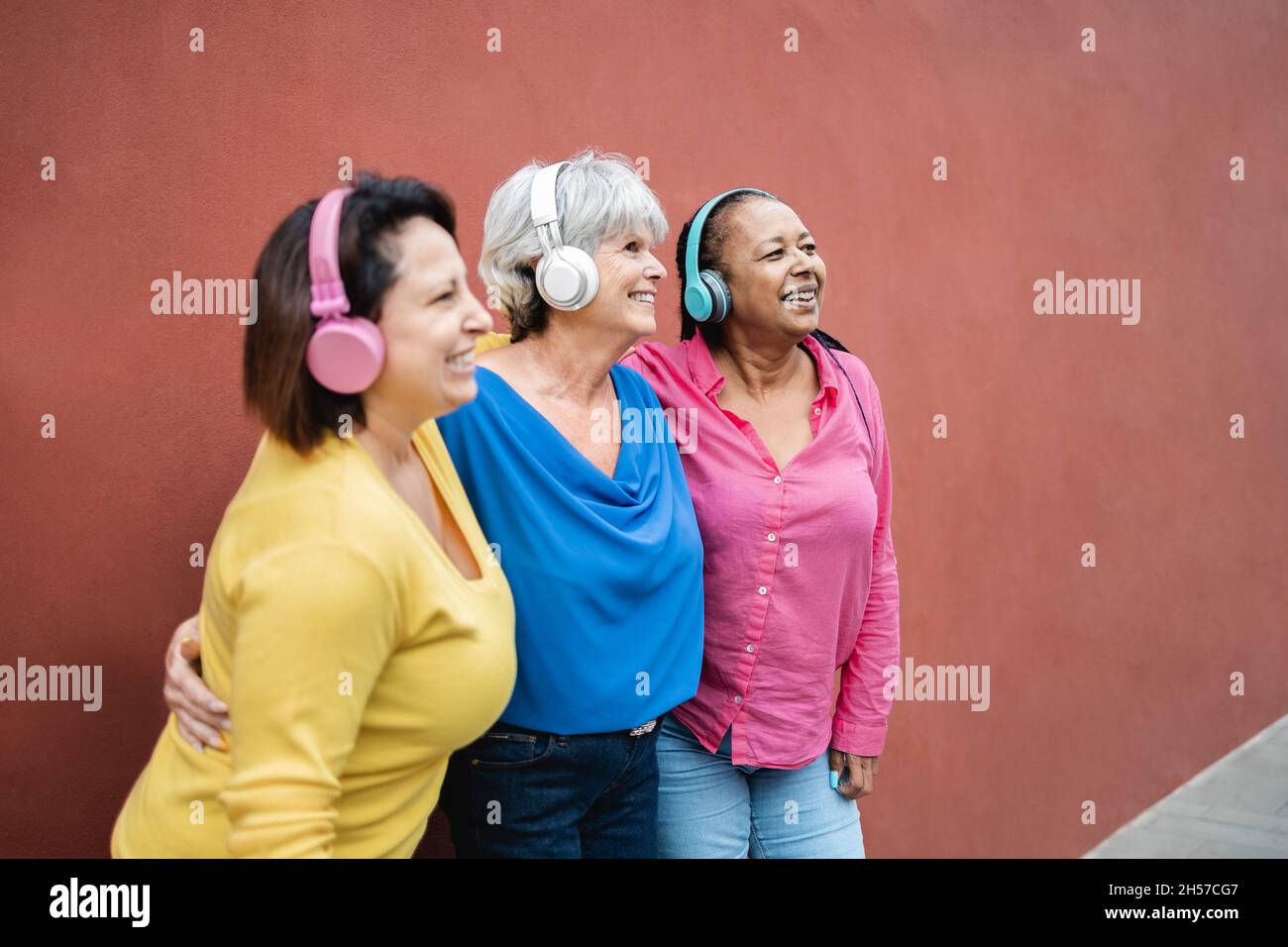 Le donne anziane multirazziali ascoltano la musica di playlist con le cuffie insieme - anziano, divertente, concetto di amicizia Foto Stock