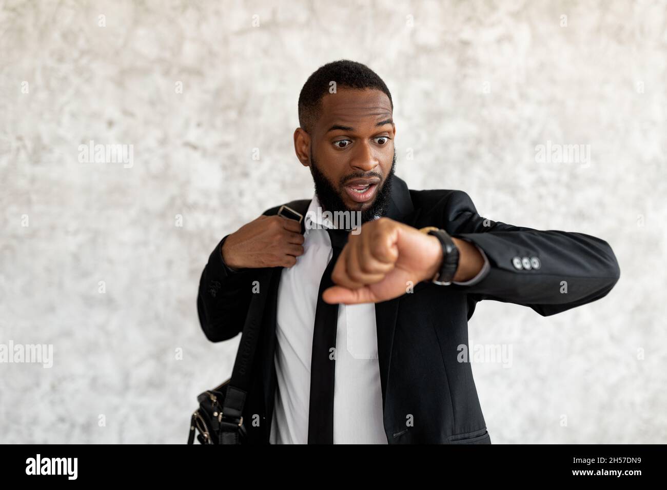 L'uomo nero spaventato è in ritardo per il lavoro guardando l'orologio Foto Stock