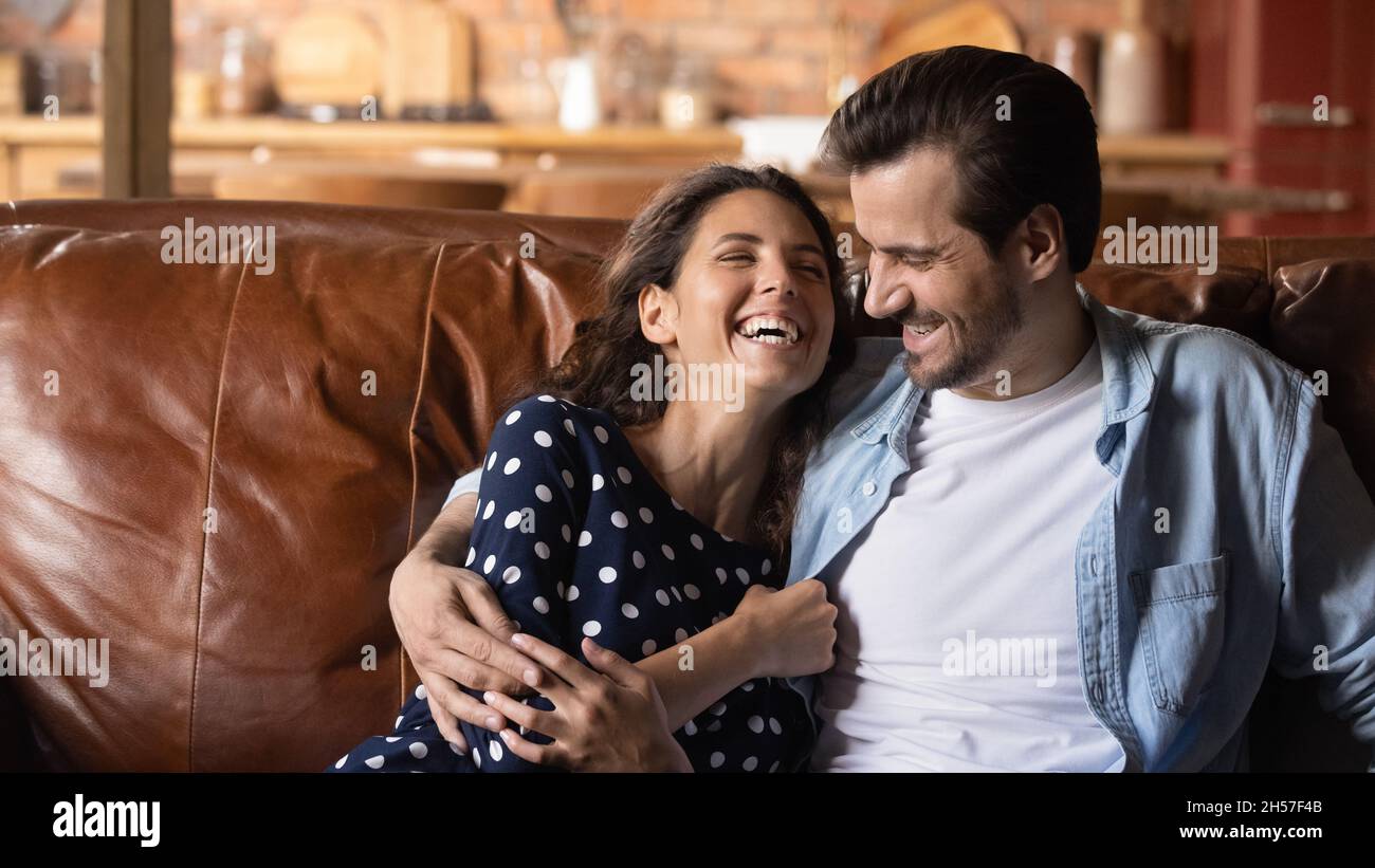 Unire le giovani spose ridere abbraccio sul divano in modo giocoso Foto Stock
