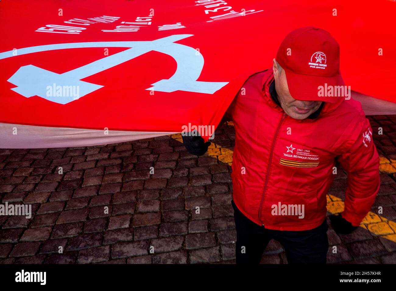 Mosca, Russia. Il 7 novembre 2021 sostenitori del partito comunista detengono un'enorme bandiera rossa mentre portano verso il Mausoleo del fondatore sovietico Vladimir Lenin sulla Piazza Rossa per celebrare il 104° anniversario della Rivoluzione del 1917 ottobre, a Mosca, in Russia Foto Stock