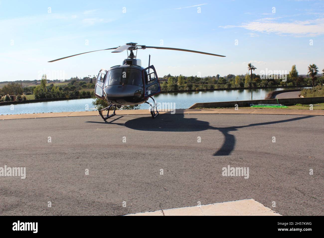 Un elicottero parcheggiato, isolato, sullo sfondo un lago e alberi, giorno di sole. Foto Stock