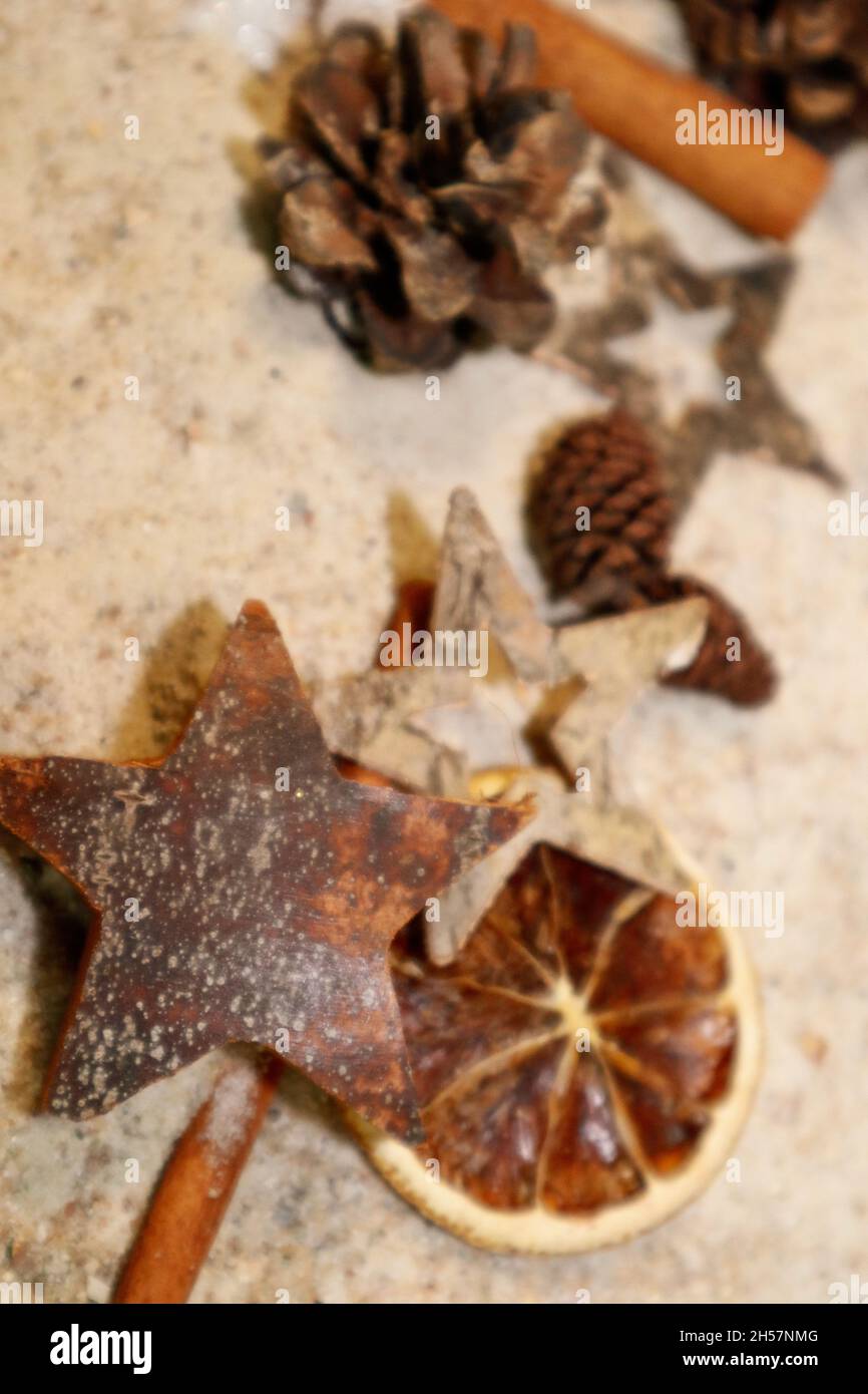 decorazioni natalizie con cannella, stelle in legno, coni di abete e fette d'arancia sulla sabbia Foto Stock