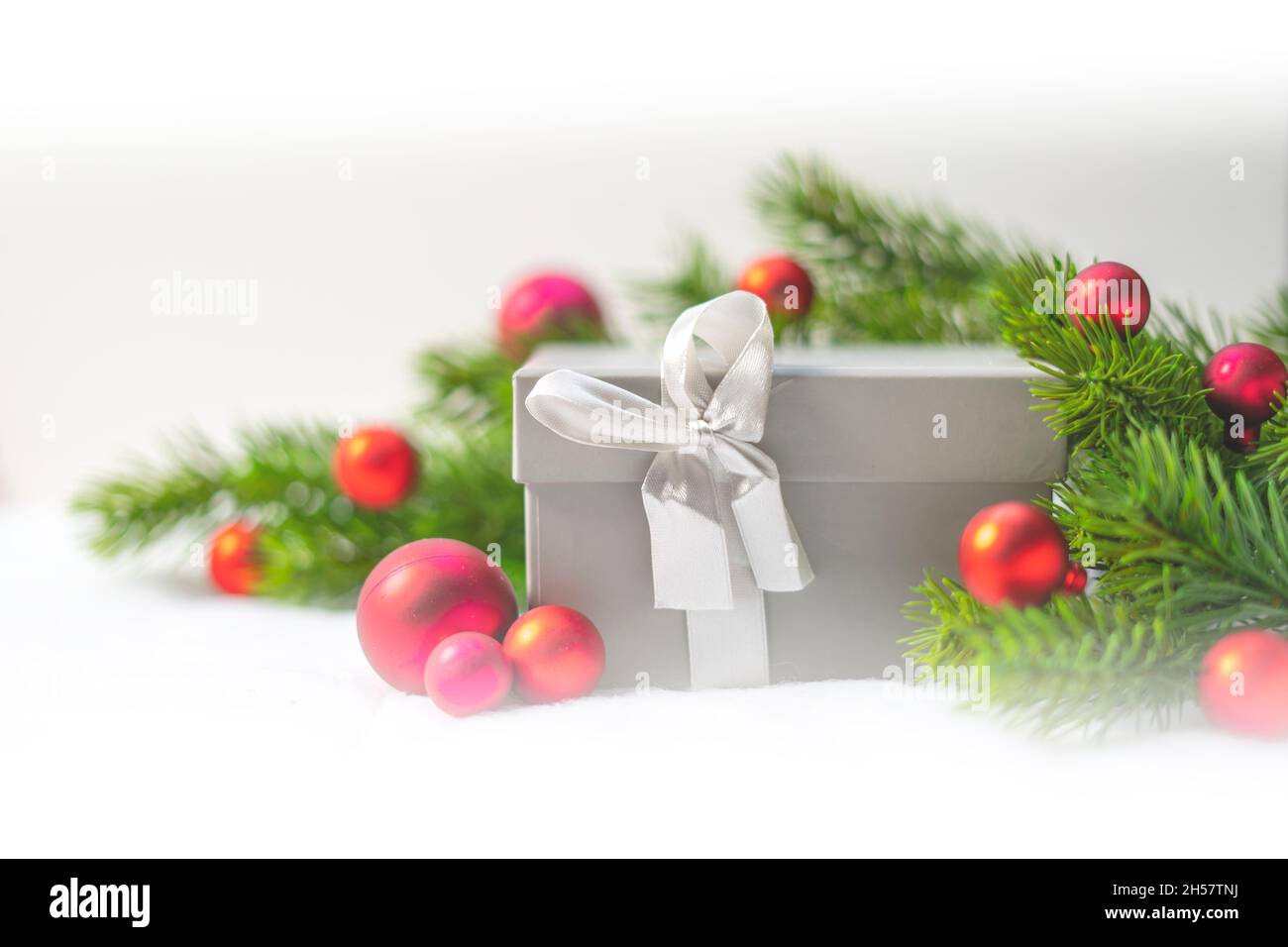 Scatola regalo in Natale. Ornamenti della sfera di Natale rossa e rami di pino o di abete. Foto Stock