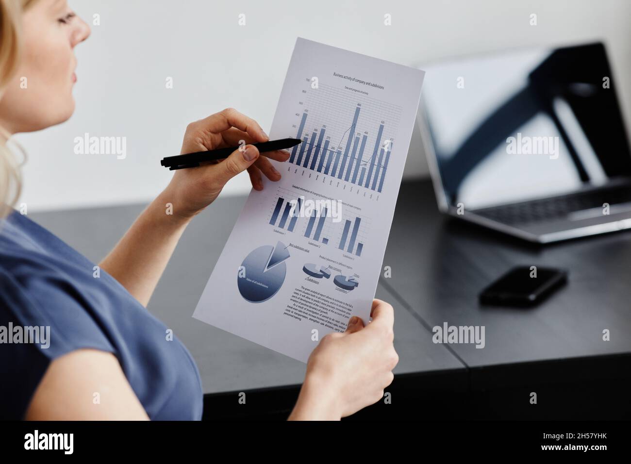 Primo piano di una donna d'affari di successo che legge i documenti dalla scrivania in un minimo interno d'ufficio, spazio di copia Foto Stock