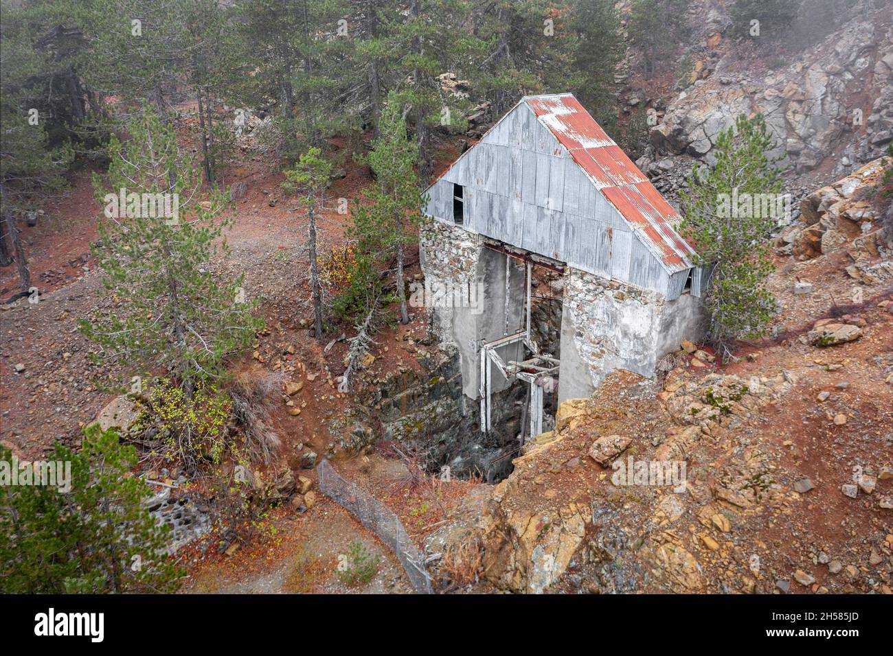 Miniera di cromite abbandonata nei monti Troodos, Cipro. Vecchio ascensore rotto su albero verticale circondato da pini Foto Stock