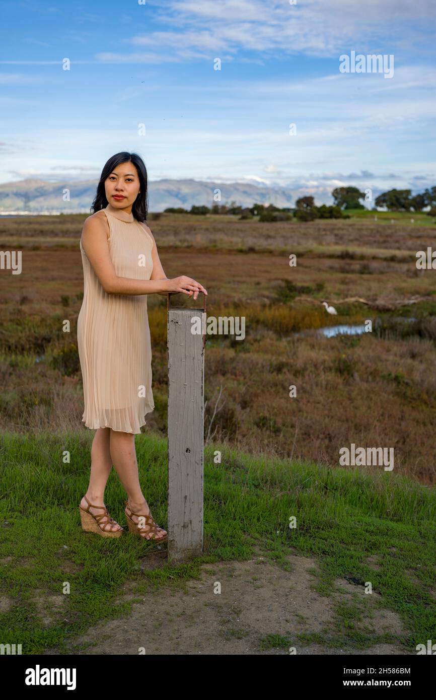 Giovane donna asiatica in un vestito di beige che cammina nelle Marshlands Foto Stock