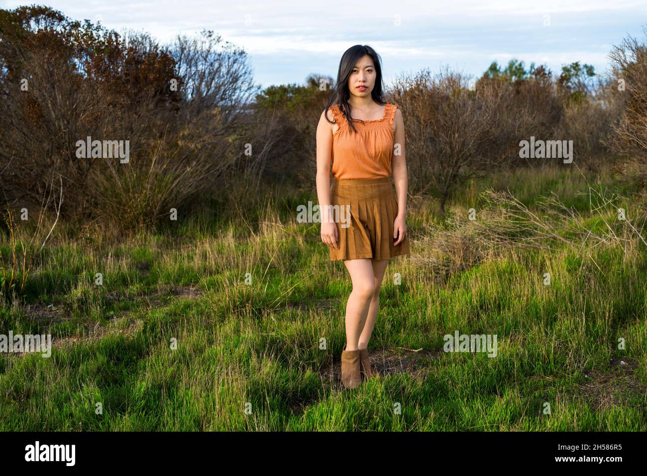 Giovane donna asiatica in colori autunnali a piedi nelle Marshlands Foto Stock