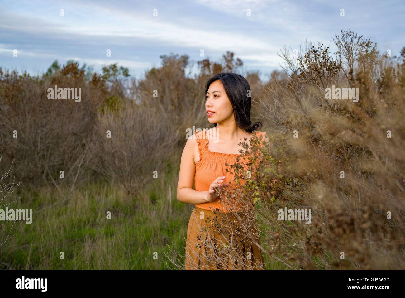 Giovane donna asiatica in colori autunnali a piedi nelle Marshlands Foto Stock
