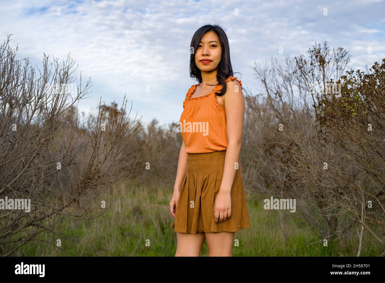 Giovane donna asiatica in colori autunnali a piedi nelle Marshlands Foto Stock