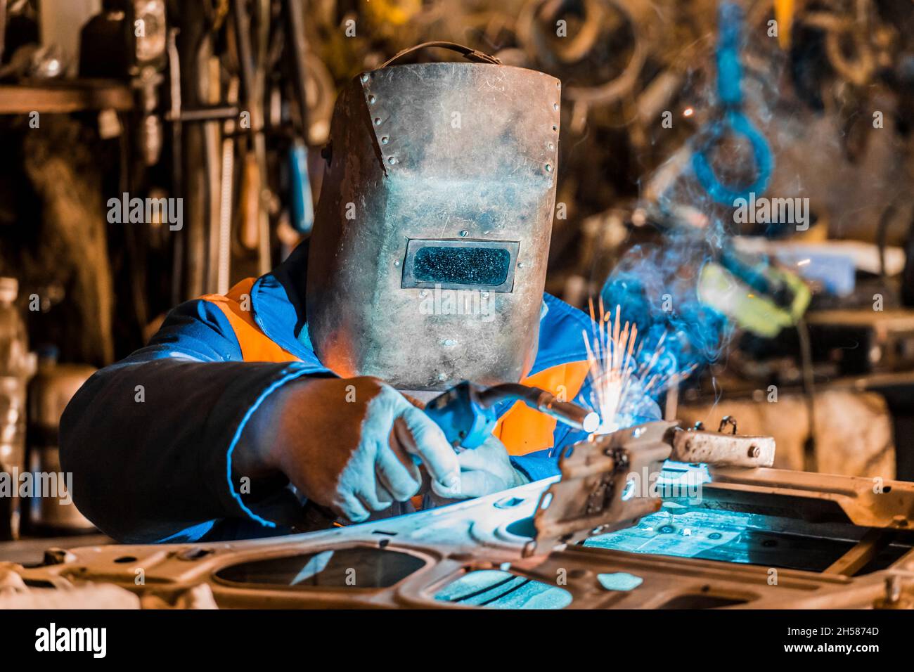 Il saldatore nello scudo è impegnato in lavori di saldatura e metallo,  riparazione della porta dell'auto presso lo stabilimento industriale Foto  stock - Alamy