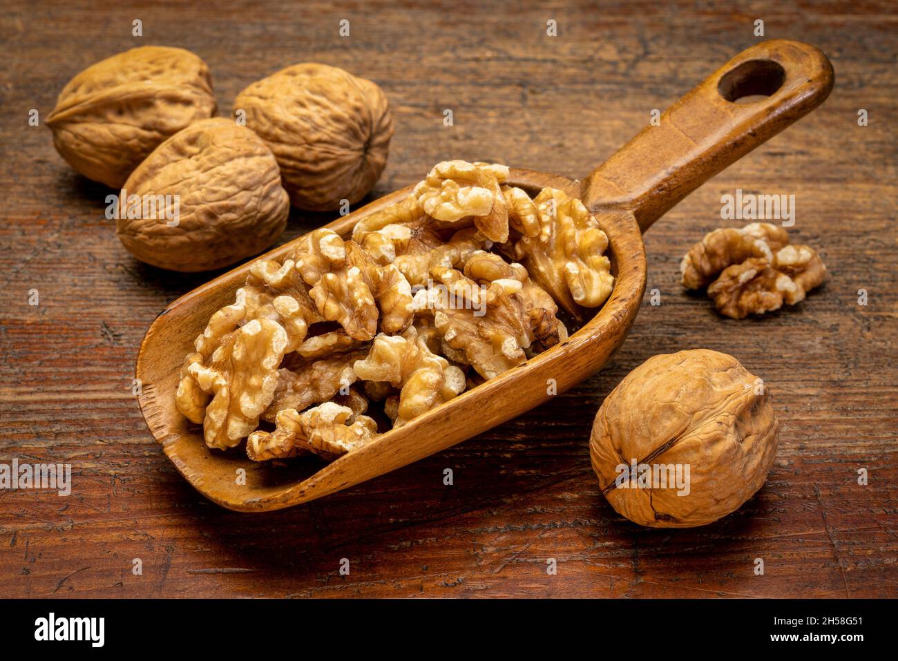 Noci inglesi su un rustico cucchiaio di legno contro grunge superficie di legno intemperato Foto Stock