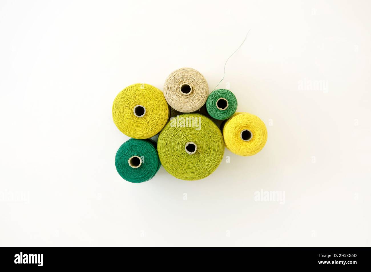 Disposizione dei fili in tonalità di verde, sfondo bianco, posa piatta. Attrezzature per progetti creativi, fai da te, hobby, lavori di progettazione. Cavo colorato Foto Stock