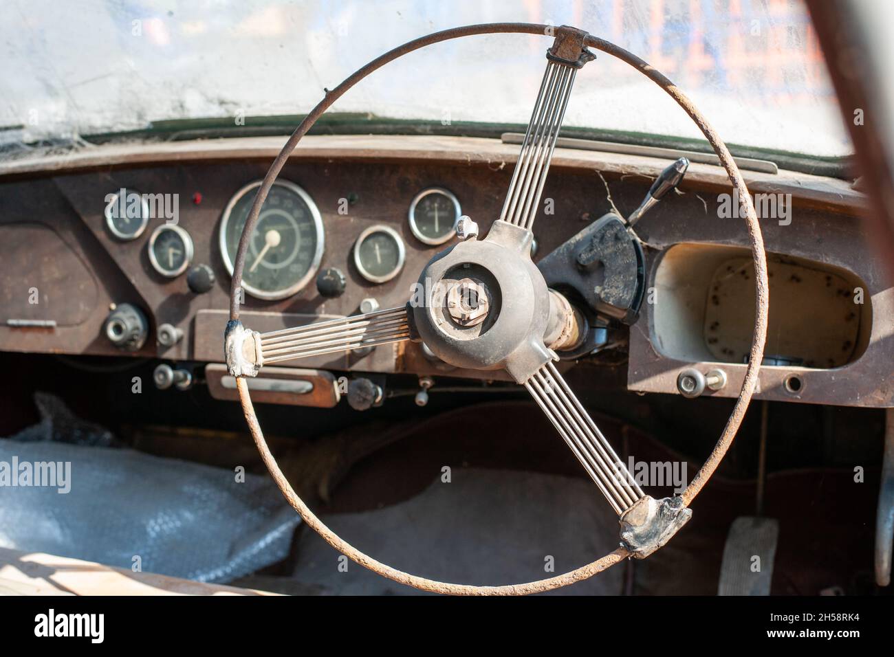 Volante e cruscotto arrugginiti di una vecchia auto dimenticata Foto Stock
