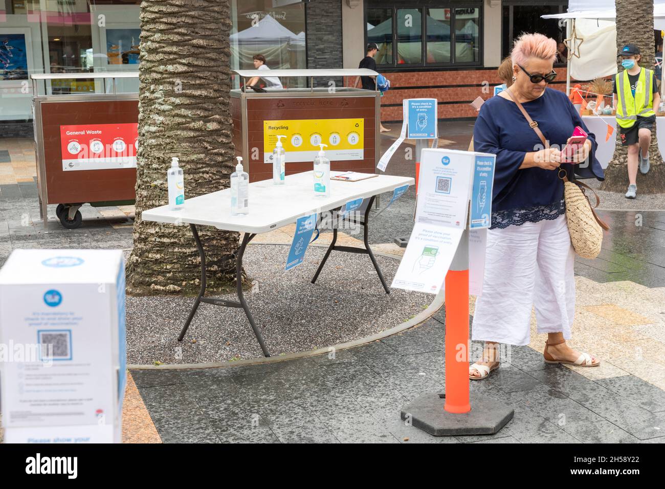 Donna che usa il suo cellulare per fare il check-in covid utilizzando il codice QR al mercato agricolo di Manly Beach a Sydney, Australia Foto Stock