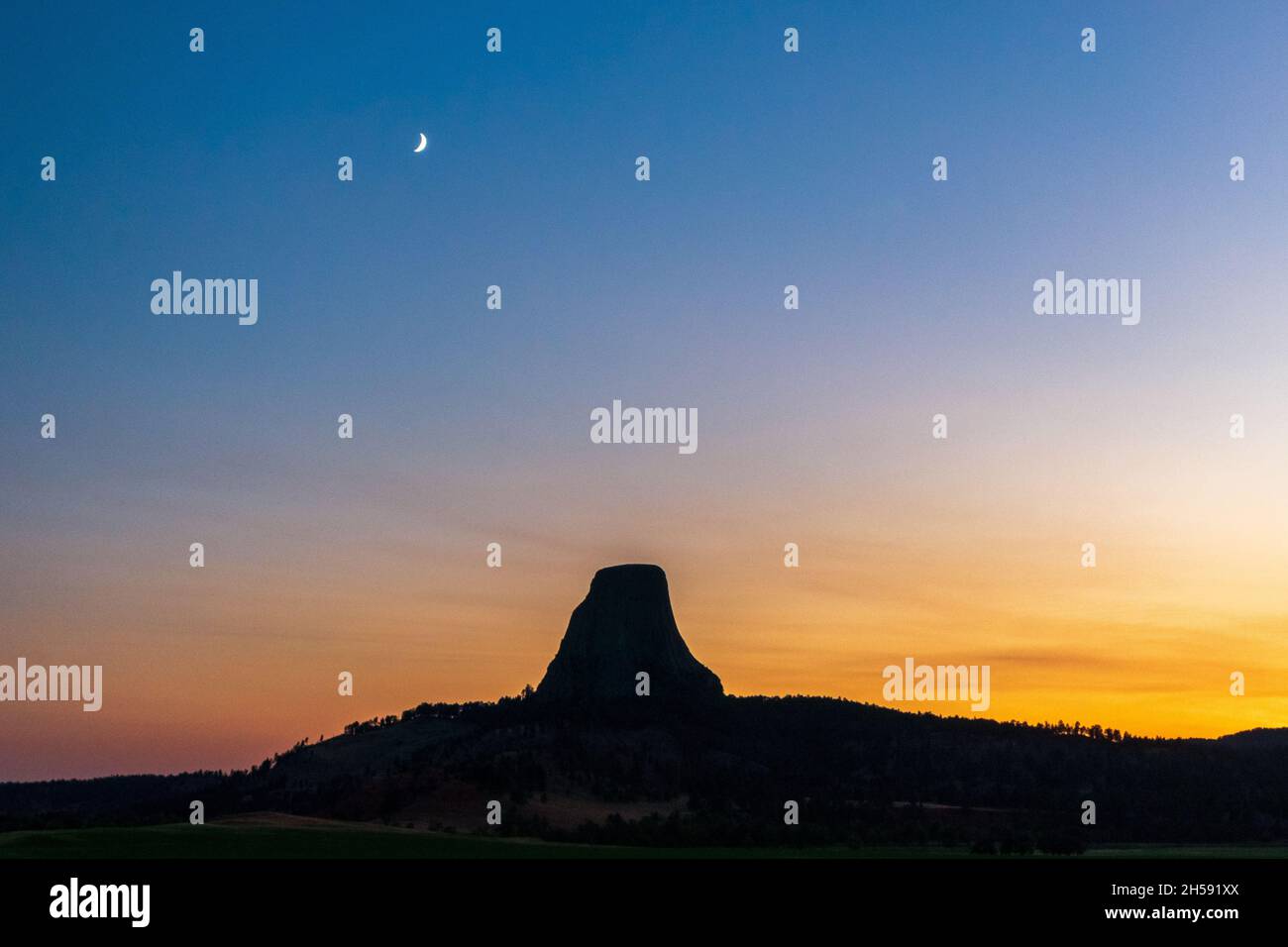 La torre dei diavoli si staglia sotto la luna al tramonto, il Devils Tower National Monument, Wyoming Foto Stock