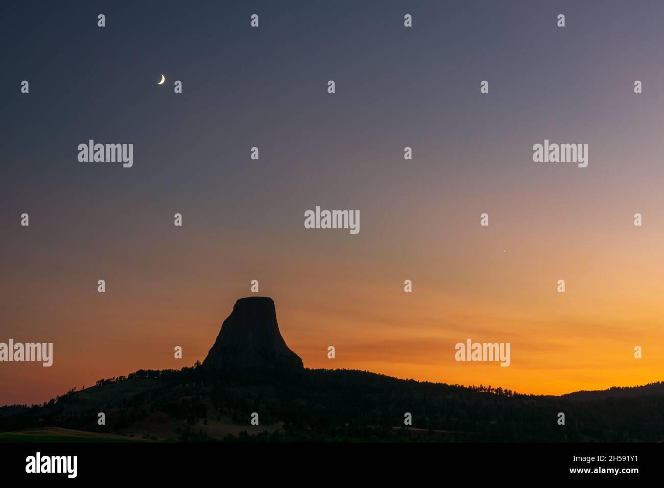 La torre dei diavoli si staglia sotto la luna al tramonto, il Devils Tower National Monument, Wyoming Foto Stock