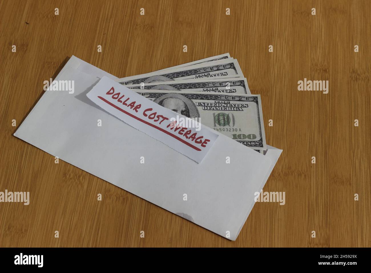 Foto concettuale, carta di denaro all'interno della busta bianca e del testo costo medio del dollaro, o investimento della regola dorata di DCA Foto Stock