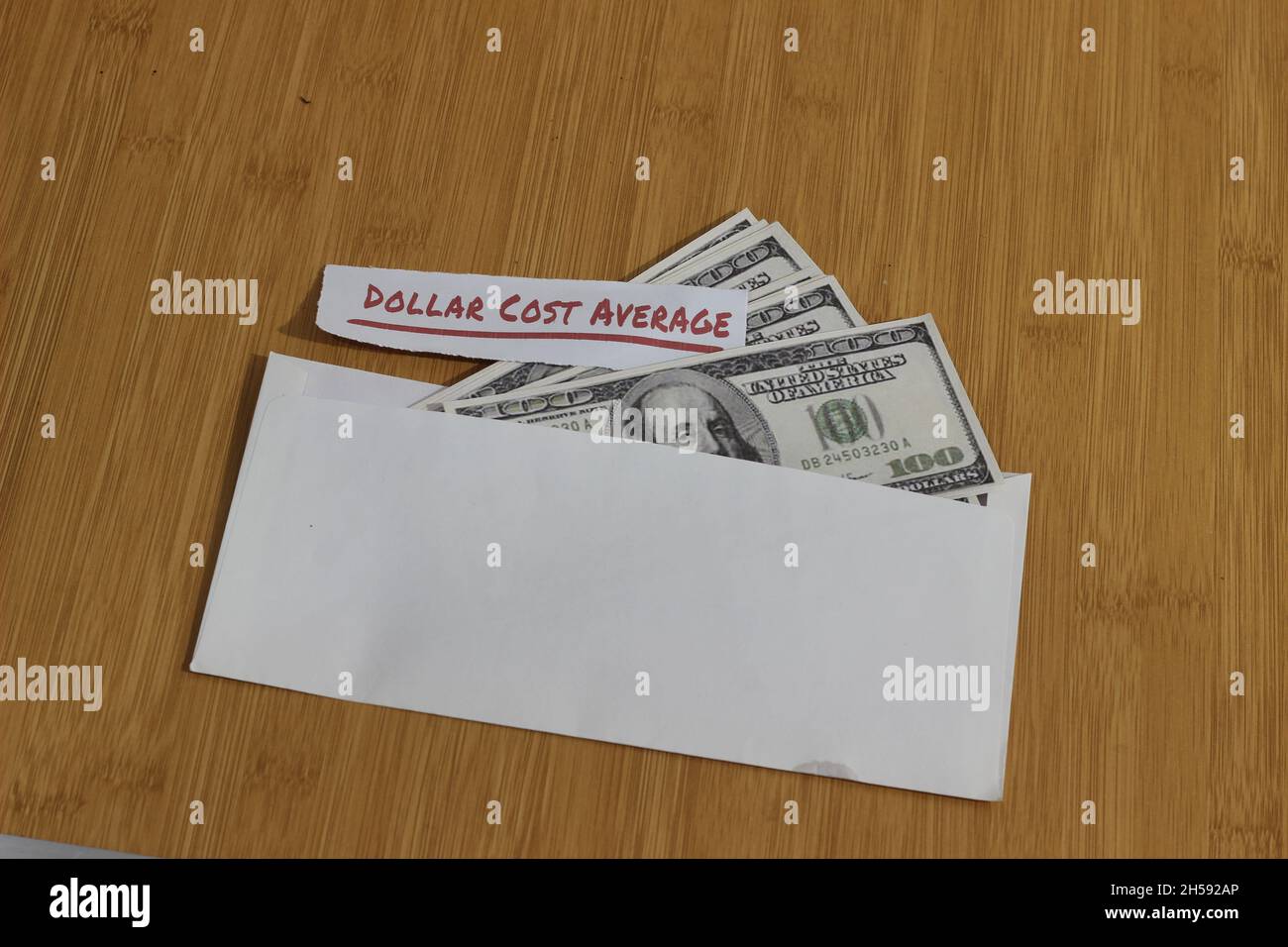 Foto concettuale, carta di denaro all'interno della busta bianca e del testo costo medio del dollaro, o investimento della regola dorata di DCA Foto Stock